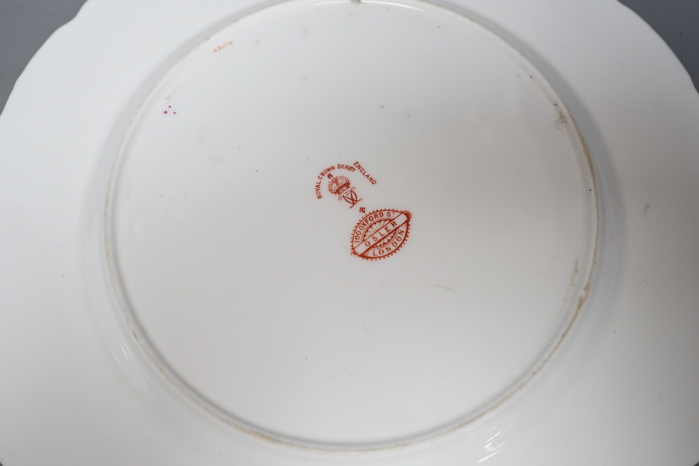 A Royal Crown Derby plate painted with fruit under claret ground by Cuthbert Gresley, signed, Made for Osler London, and a Derby King Street plate with roses